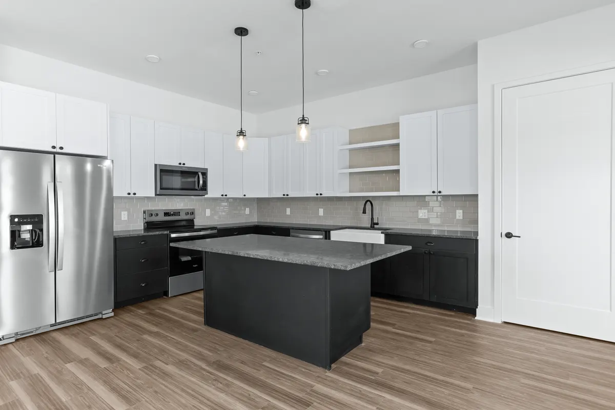 Modern kitchen with quartz island, stainless appliances, and white cabinetry